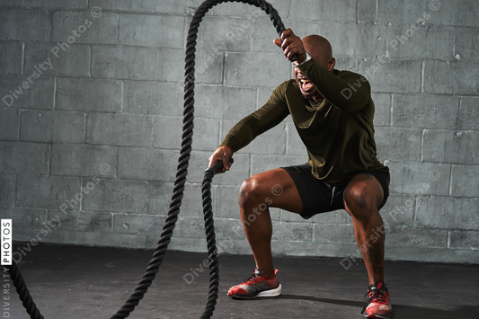 Black man training with battle ropes in crossfit