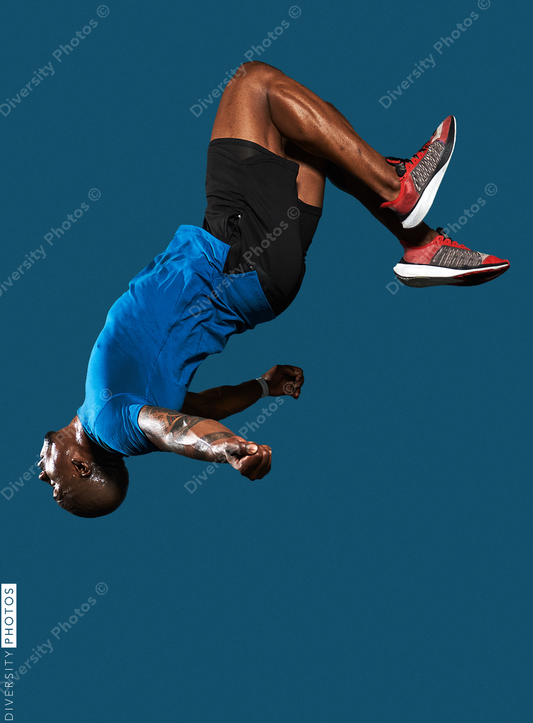 Black man jumps and does backflip on blue background