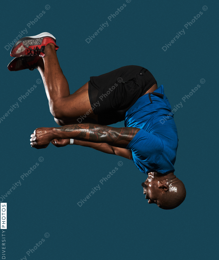Black man jumps and does backflip on blue background