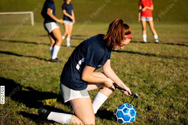 Girl pumping up soccer ball