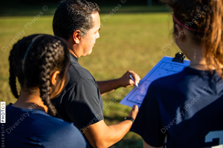 Teenage soccer coach teaches plays with female team