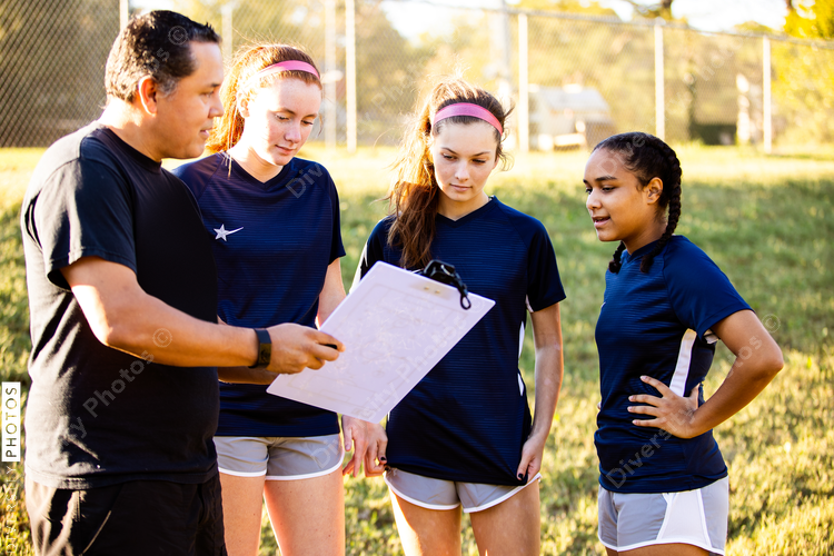 Teenage soccer coach teaches plays with female team