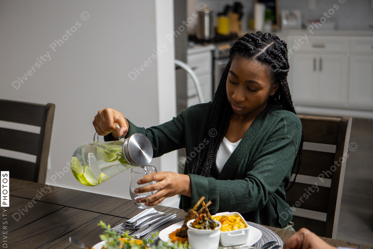 Teen girl pours water drink at dinner table