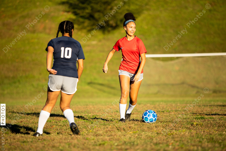 Female soccer player running by defender