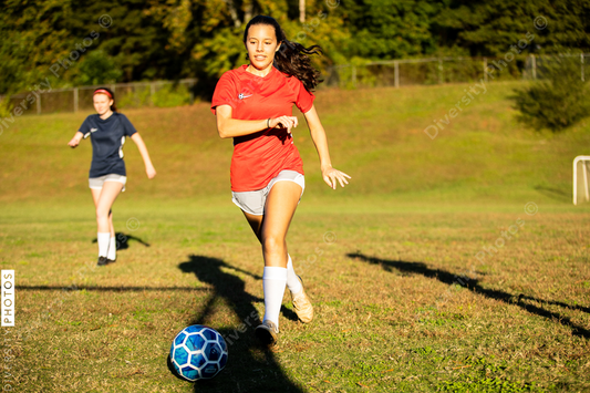 Young Hispanic female runs after soccer ball