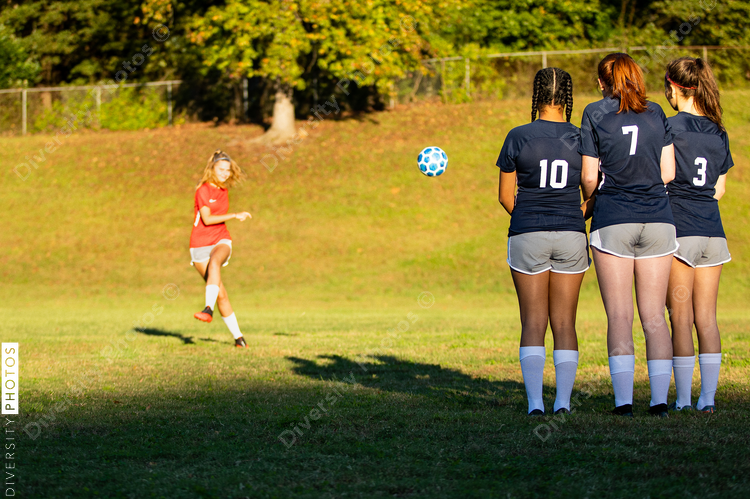 Girl kicking soccer ball in game