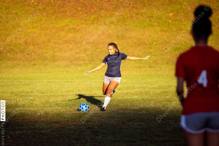 Girl kicking soccer ball in game