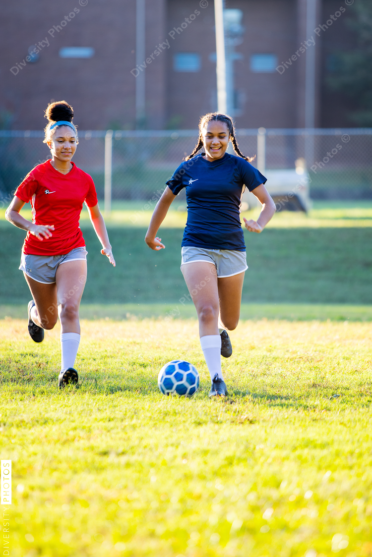 Teenage girl soccer players running after ball