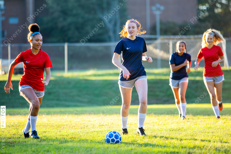 Teenage girl soccer players running after ball