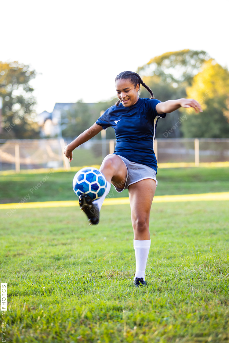 Mixed race female soccer player kicking ball