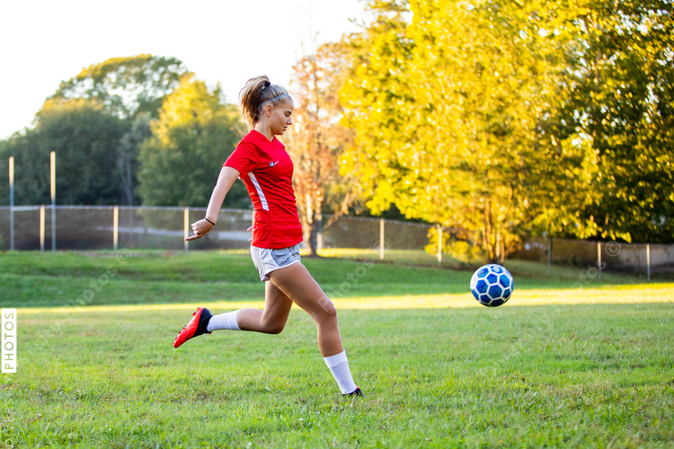Teen girl soccer player kicking ball