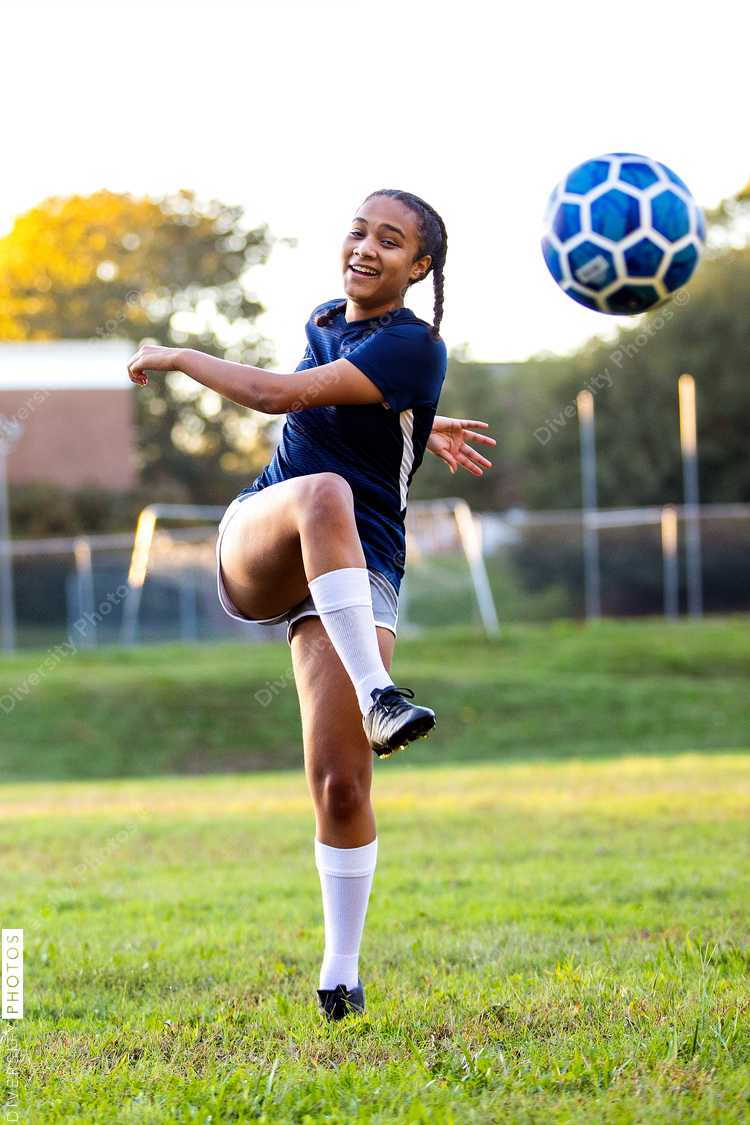 Mixed race female soccer player kicking ball