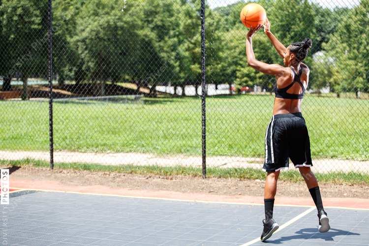Woman in black trying to throw basketball