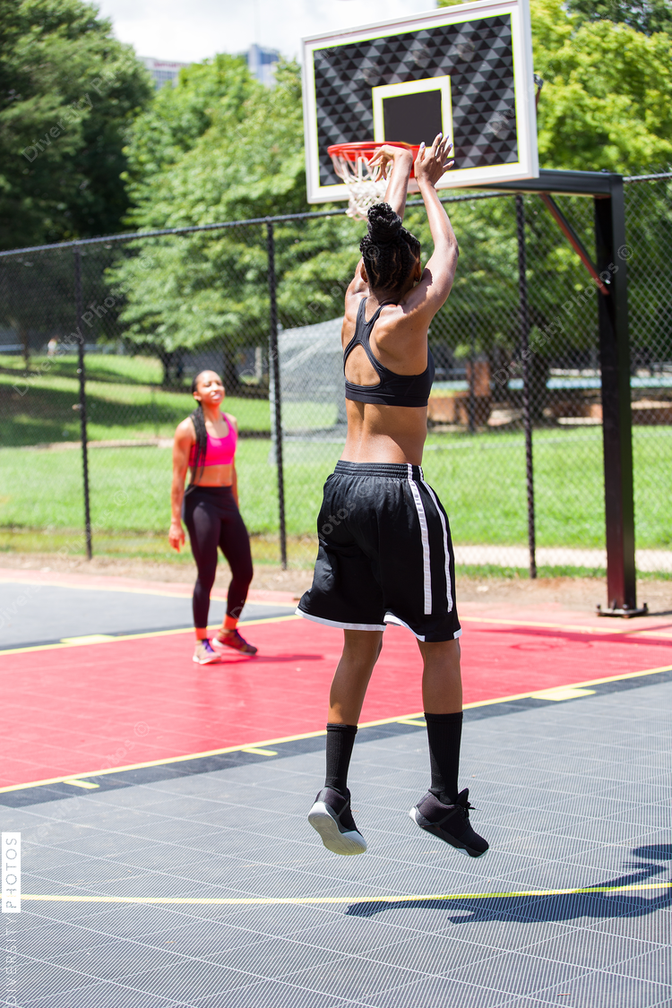 Woman jumping and throwing basketball into net