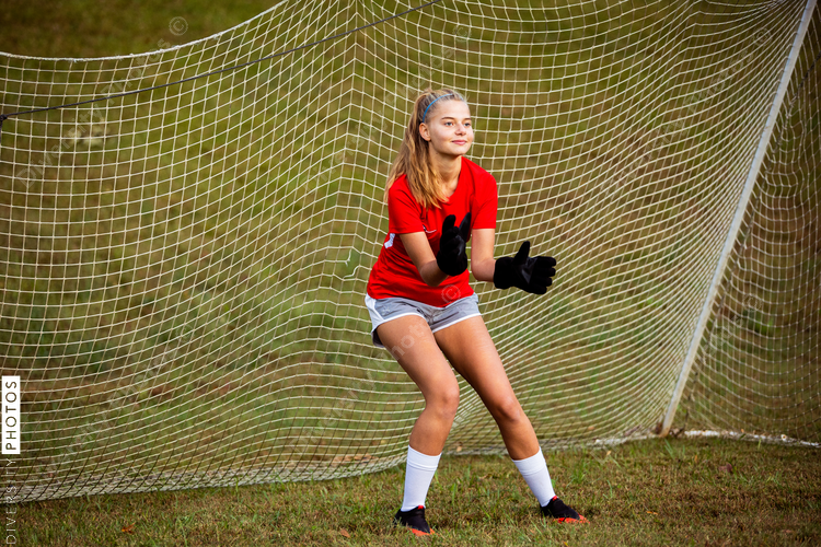 Teenage girl playing goalie on soccer field