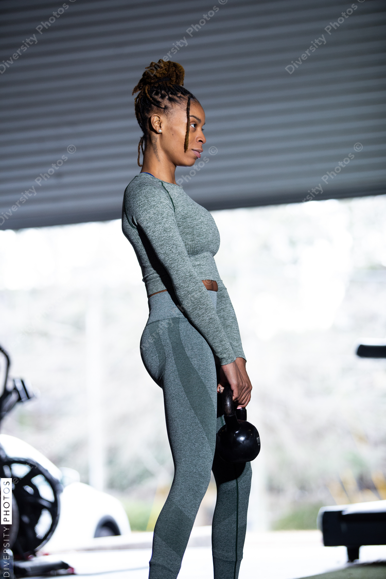 Black woman does exercises in gym, squat, kettleball swing