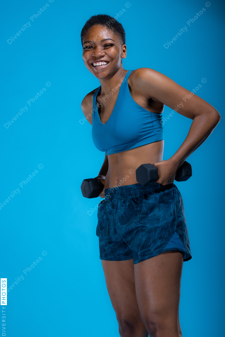 Portrait of pretty Black woman doing dumbbell exercises 