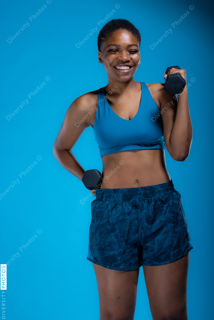 Portrait of pretty Black woman doing dumbbell exercises 