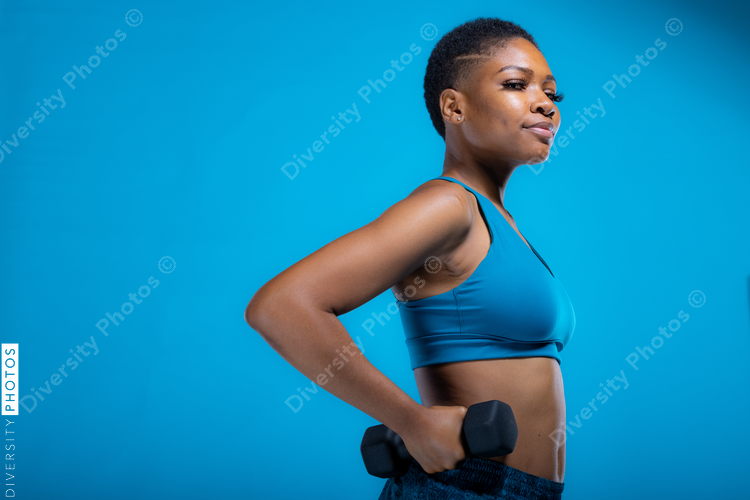 Portrait of pretty African American woman doing dumbbell exercises 