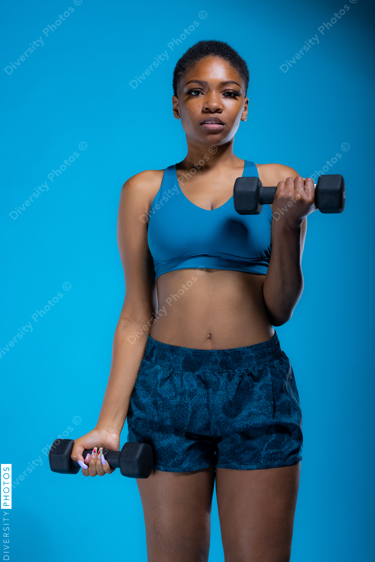 Portrait of pretty African American woman doing dumbbell exercises 