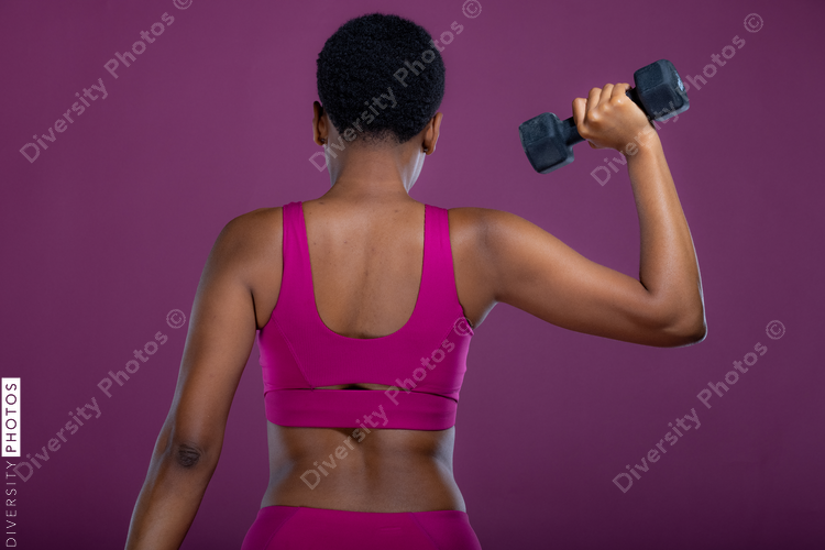 Rear view of Black woman doing dumbbell exercises 