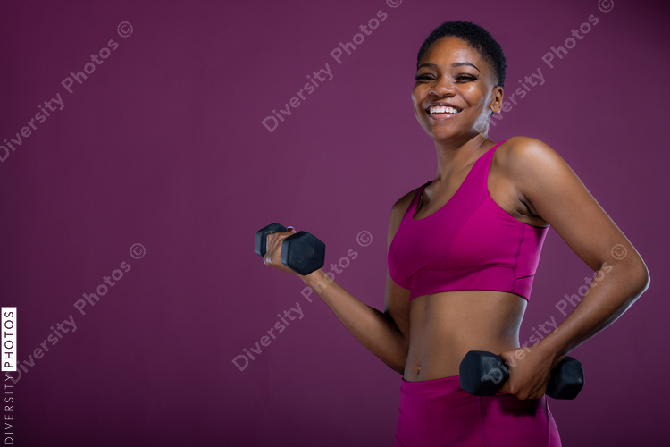 Smiling Black woman workout with dumbbells and copy-space
