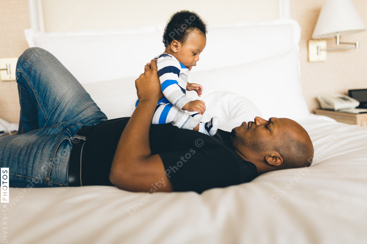 Father playing with his son on bed at home
