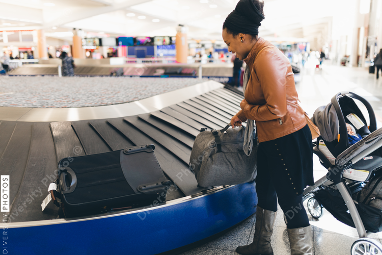 Woman picking up luggage from baggage carousel at airport