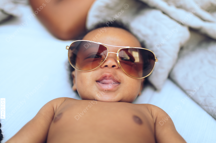 Smiling baby wears oversize sunglasses