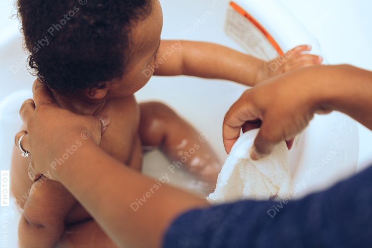 Mother props up baby in bathtub