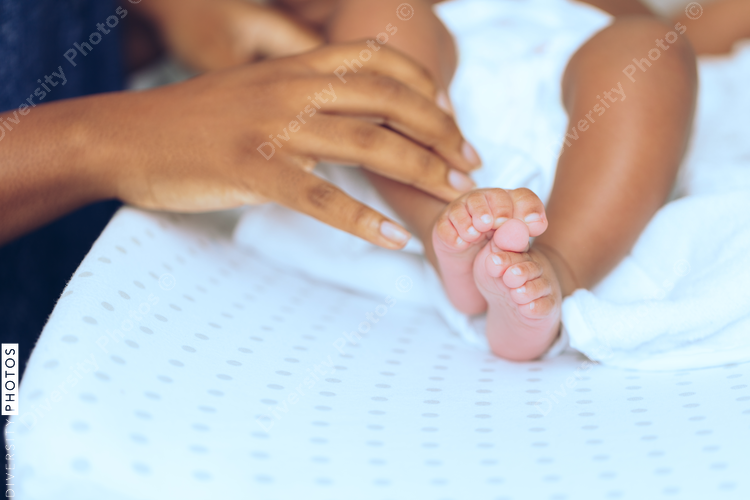 Close up of mother's hand touching baby's leg