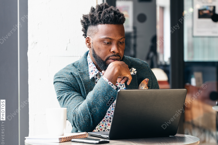 Businessman with chin on hand in front of laptop