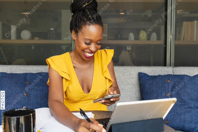 Smiling businesswoman looks at phone in front of laptop
