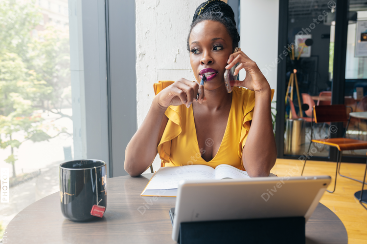 Businesswoman talks on phone and holds pen to mouth