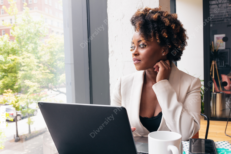 Businesswoman looks out window while sitting by laptop