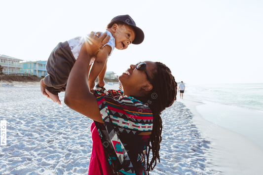 Black mom entertaining baby on beach