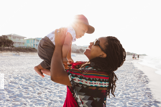 Black mom entertaining baby on beach