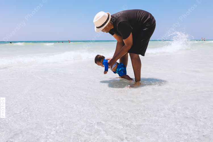 Black father playing with son in shallow water