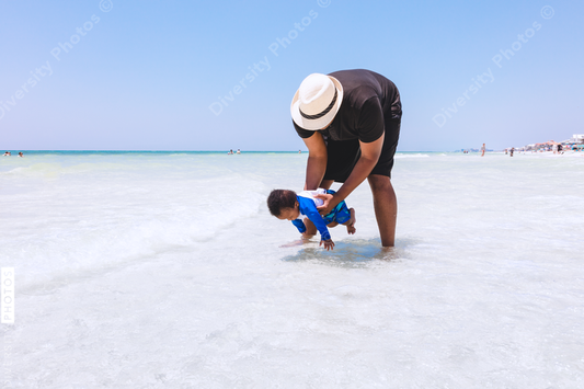 Black father playing with son in shallow water