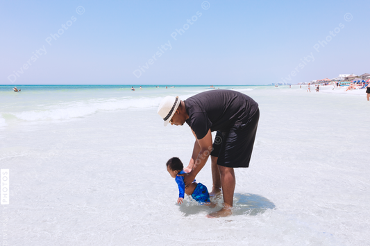 Black father playing with son in shallow water