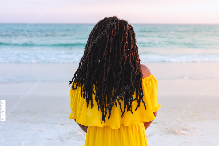 Black woman in pretty sun dress on the beach