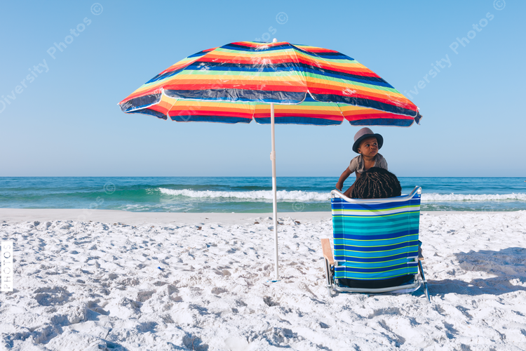 Black mother and son sitting on beach