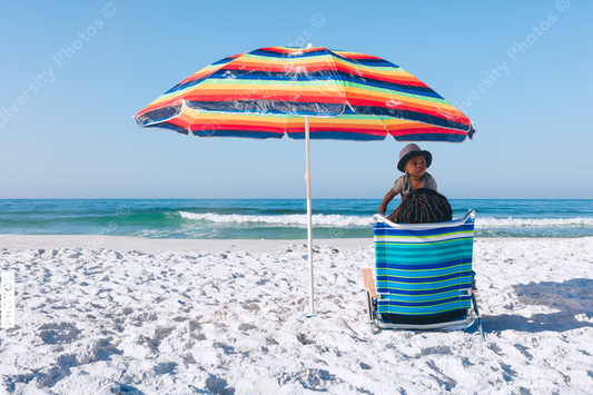 Black mother and son sitting on beach
