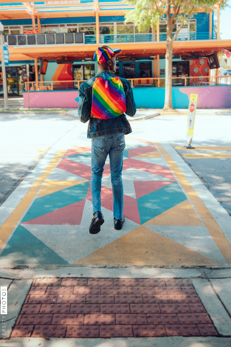 Rear view of man with rainbow backpack and baseball cap