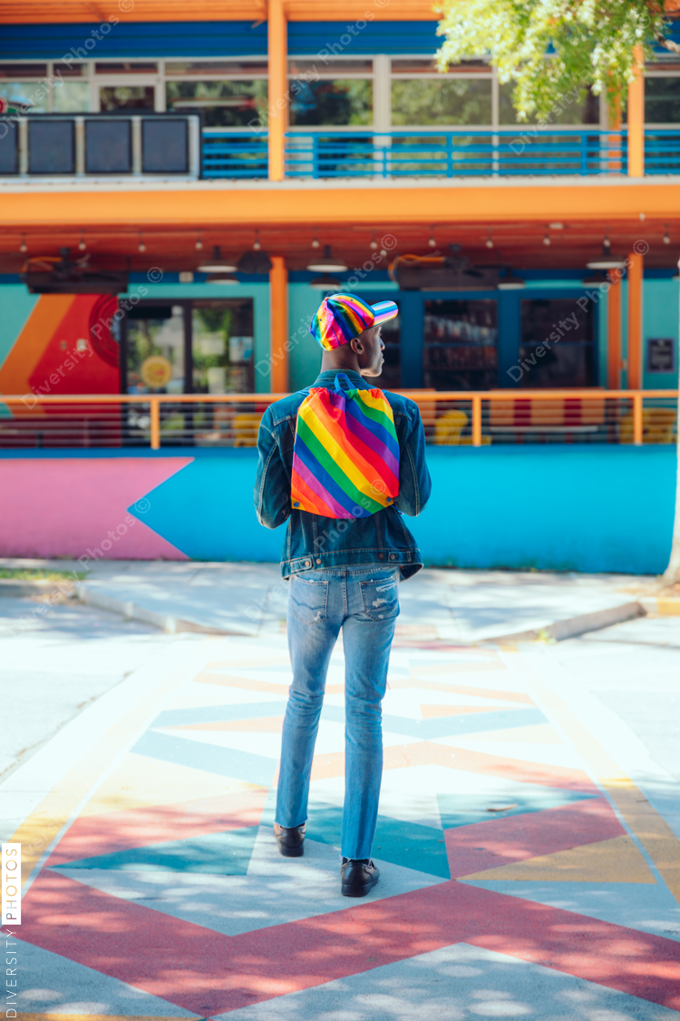 Rear view of man with rainbow backpack and baseball cap