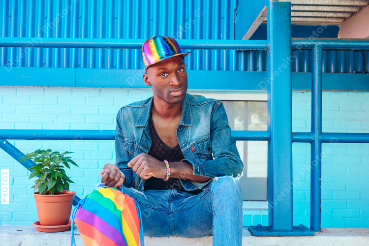 Young man in jean jacket and rainbow baseball cap