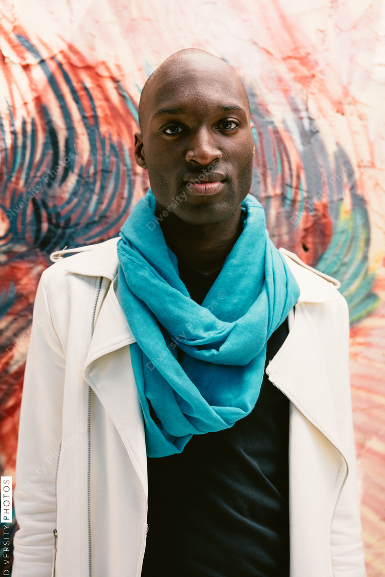 Young man wearing turquoise scarf in front of abstract painting