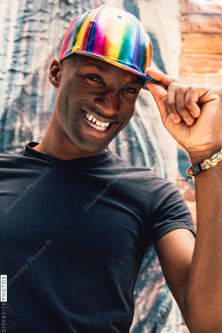Close up of man wearing rainbow baseball cap and laughing