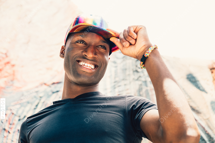 Low angle view of man wearing rainbow baseball cap and smiling