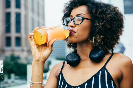 Young woman drinking orange juice from glass bottle